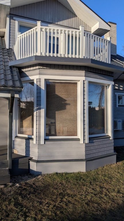 Grey timber façade, bay window and white balcony railing