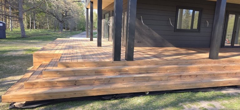 Heat-oiled timber terrace with steps by a dark façade
