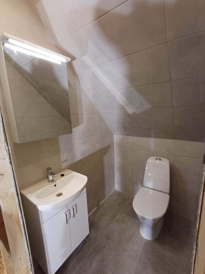 Small bathroom with vanity, mirrored cabinet and toilet under a sloped ceiling